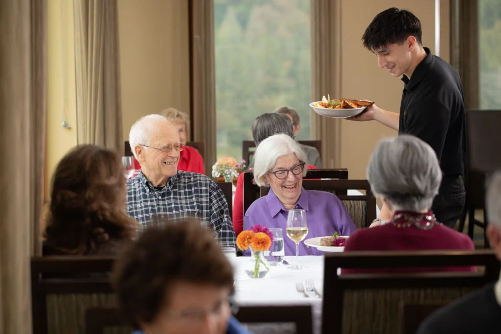 senior couple of man and woman dining at Timber Ridge with waiter serving them