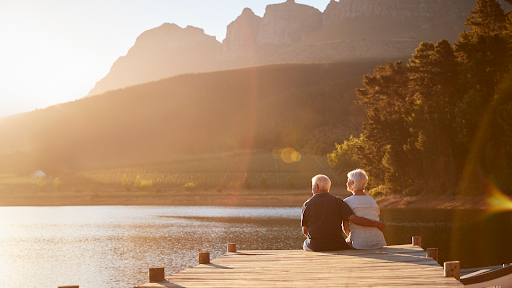 Couple sitting together by the water and mountain in retirement