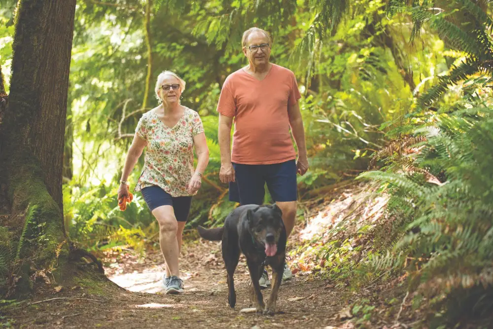 a Timber Ridge at Talus senior couple walking their dog on a hiking trail