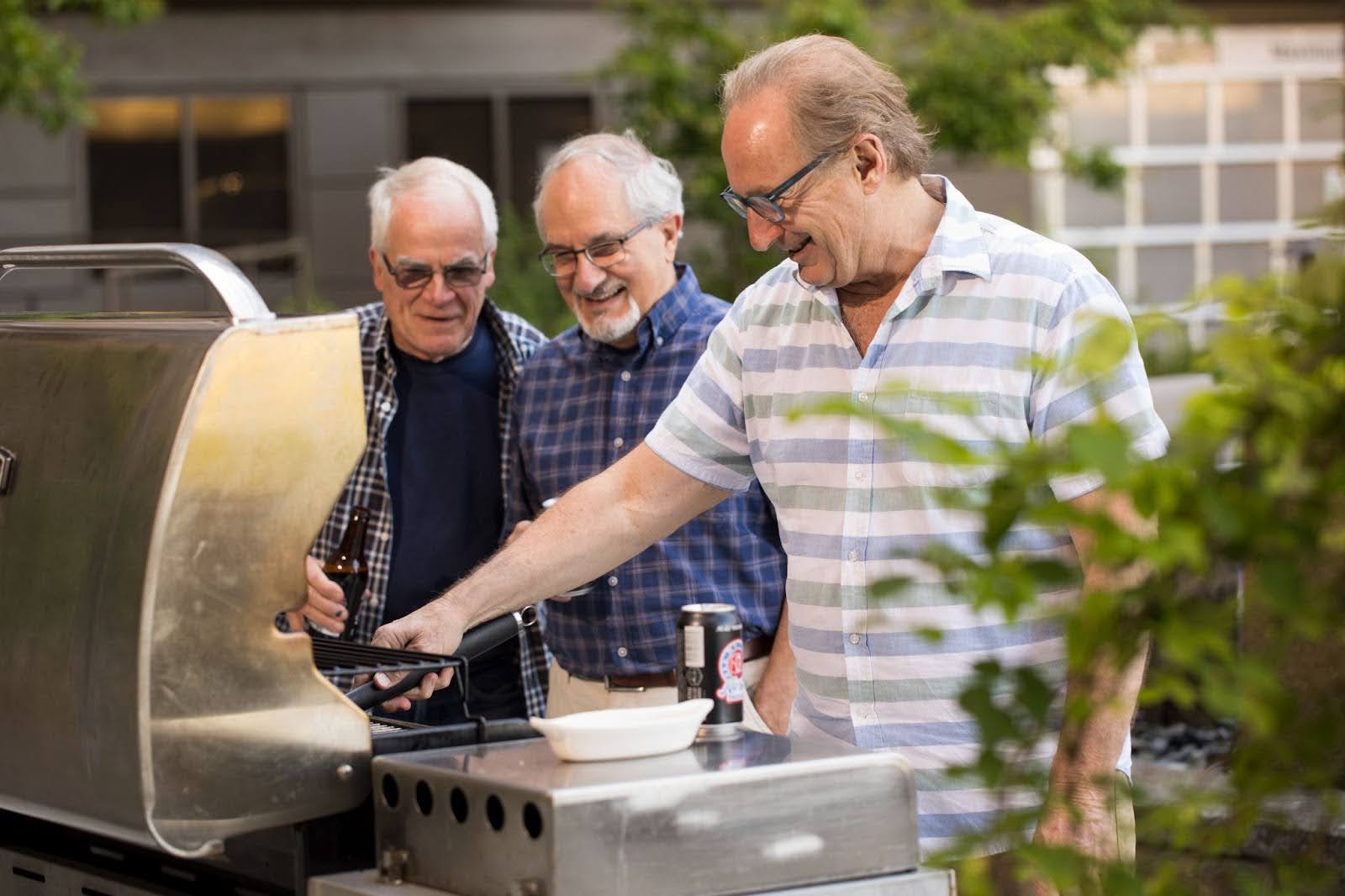 Three senior men cooking out on the grill.