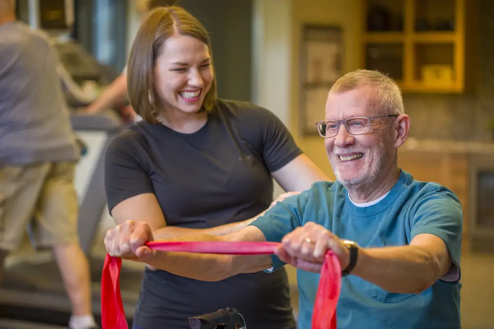 a senior man exercising with a resistance band with the help of his fitness instructor