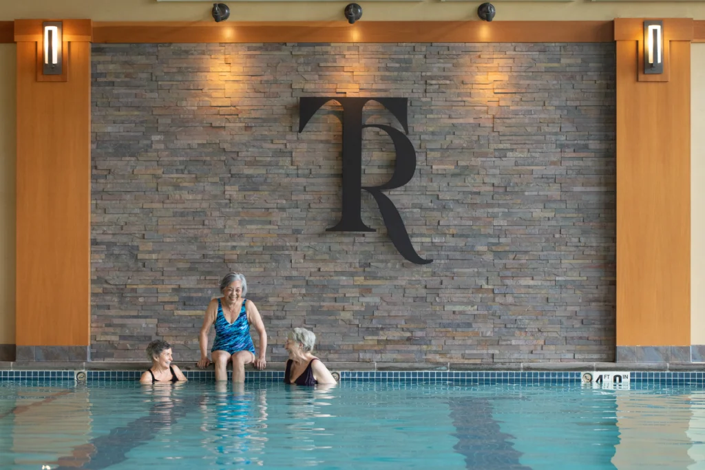 Three seniors in a pool enjoying the amenities at Timber Ridge at Talus, a life plan community in Issaquah, WA.