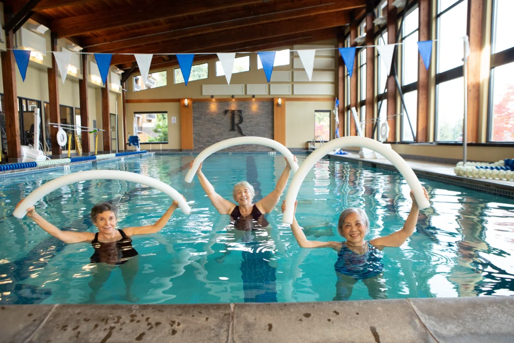 senior women working out with water aerobic exercises in pool at Timber Ridge at Talus, some of the luxury senior living amenities they have.