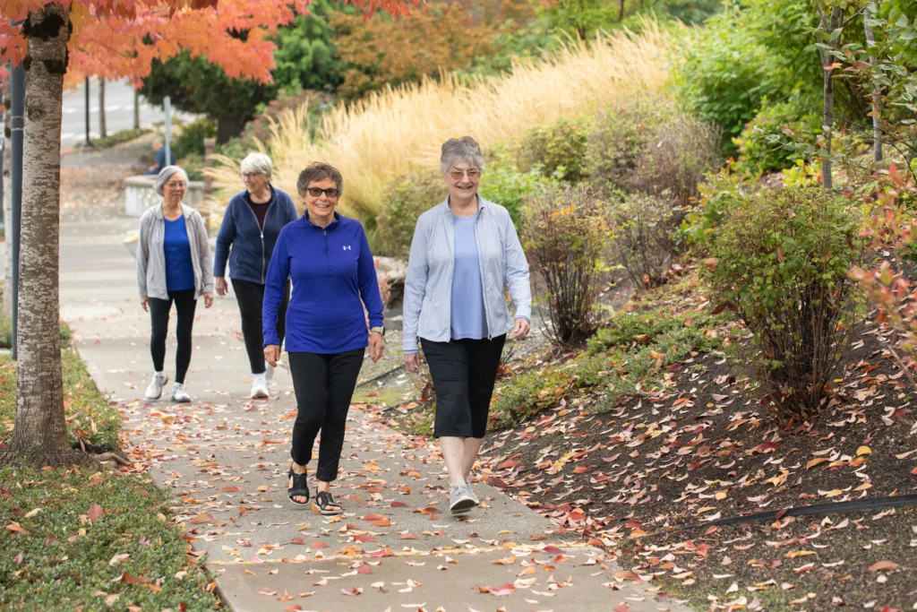 Residents of Timber Ridge at Talus walking on a sidewalk, exploring senior-friendly trail in Issaquah, Washington. 
