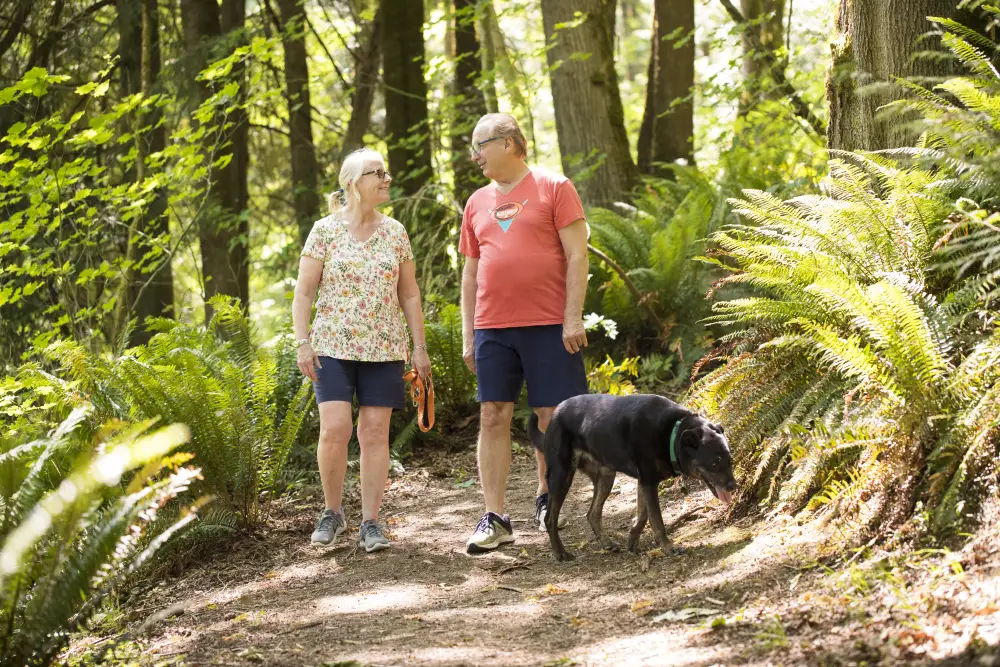 a senior couple walking their dog on a hiking trail