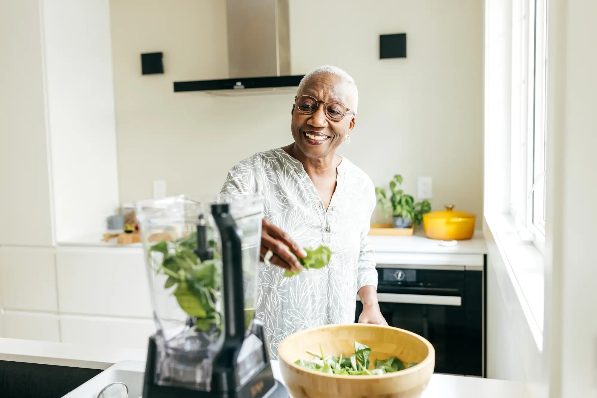 senior black woman making a healthy smoothie in kitchen
