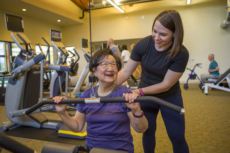 Senior resident and physical trainer working out.