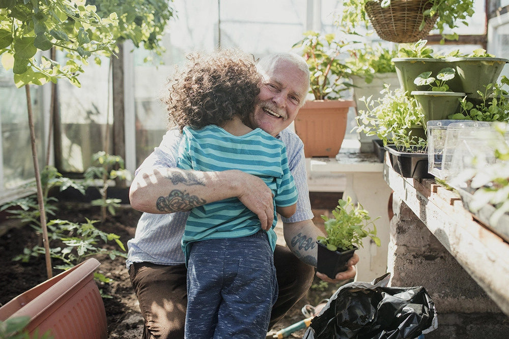 senior man with tattoos in a greenhouse with grand child