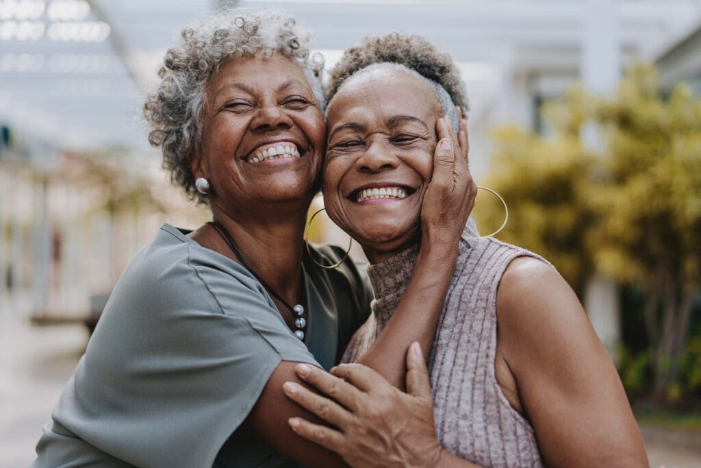 two senior women smiling and hugging