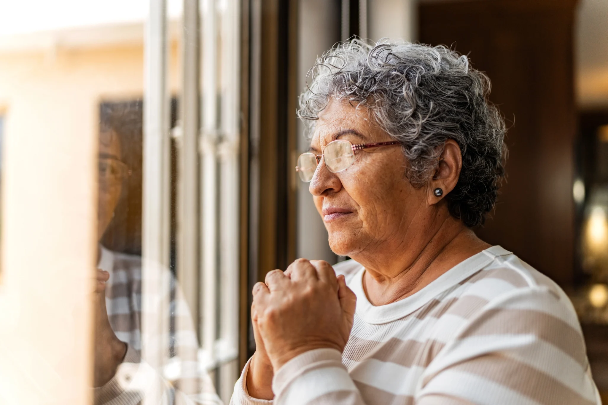 woman with retirement anxiety looking out her window at Timber Ridge at Talus in Issaquah, WA.