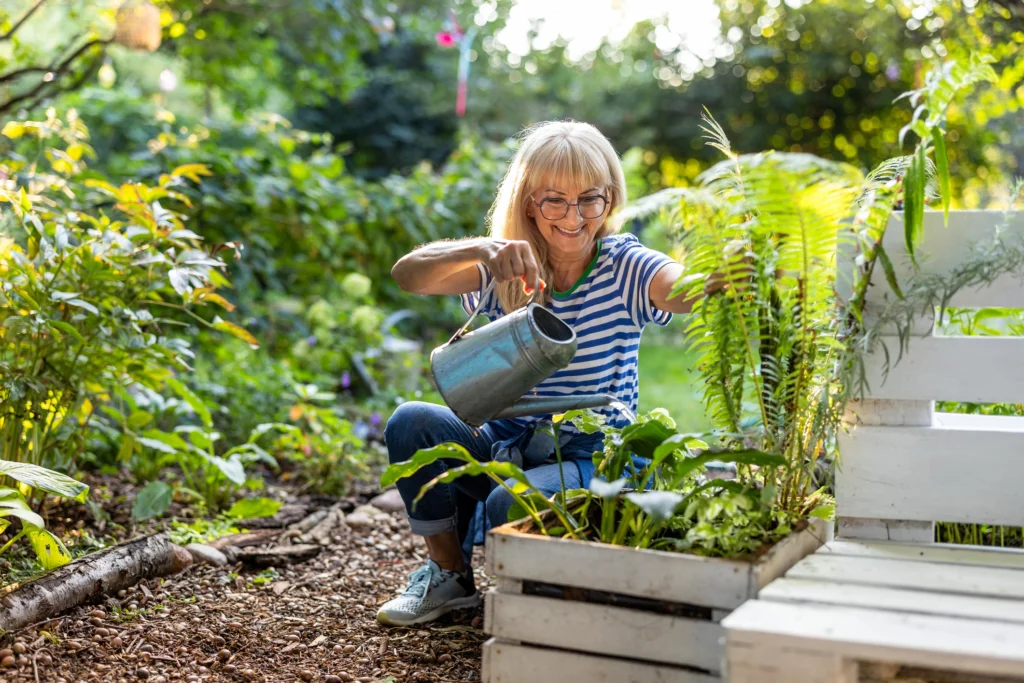 A senior woman gardening and water her plant in her home at Timber Ridge at Talus, a life plan community in Issaquah, WA.